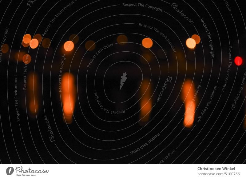 Lichtpunkte in der Dunkelheit mit Spiegelung im Wasser Bokeh Unschärfe verschwommen Hintergrund unscharf abstrakt Lichter glänzend orange Farbenspiel