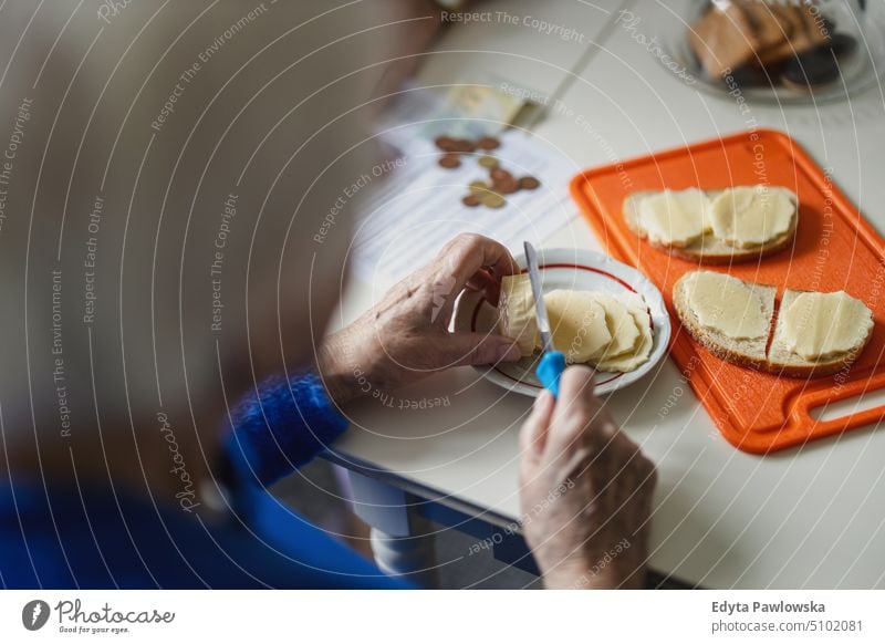 Nahaufnahme der Hände einer älteren Frau, die in der Küche Brötchen schmiert Menschen Senior reif heimwärts Haus alt Alterung häusliches Leben Großmutter