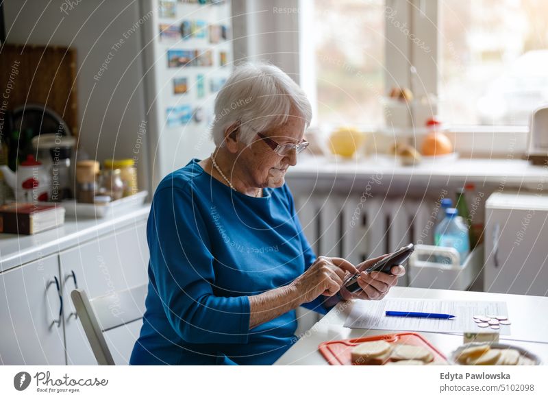 Ältere Frau benutzt Mobiltelefon zu Hause Lächeln Glück genießend positiv Freude Menschen Senior reif älter heimwärts alt Alterung häusliches Leben Großmutter