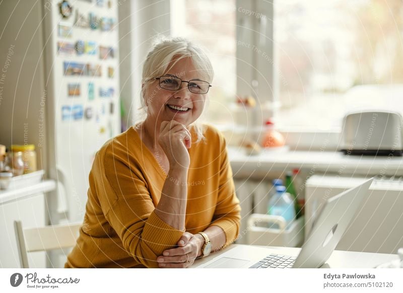 Reife Frau arbeitet am Laptop in der Küche Lächeln Glück genießend positiv Freude Menschen Senior reif älter heimwärts Haus alt Alterung häusliches Leben