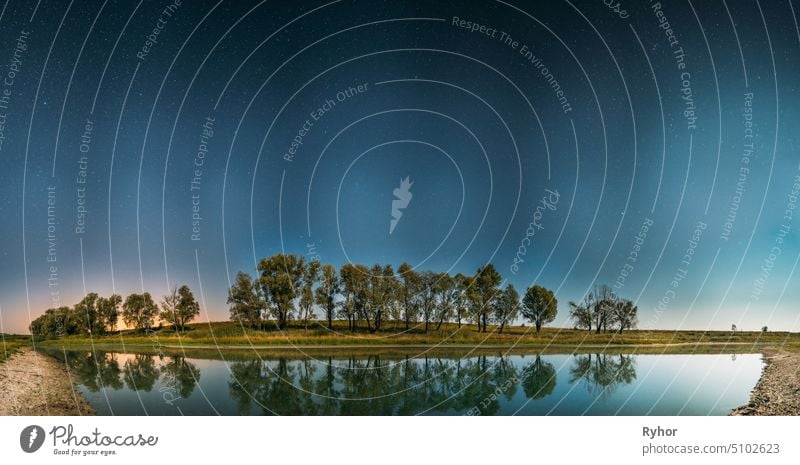 Night Starry Sky Above Lake River. Nacht leuchtenden Sternen und Bäumen Wälder im Wasser reflektiert. Nacht-Landschaft. Panorama Glühende Sterne sternenklar