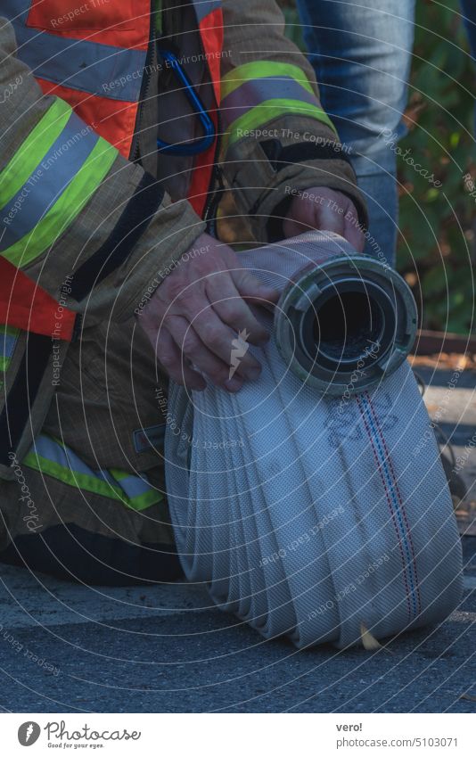 Feuerwehrmann mit aufgerolltem Schlauch Brandschutz Lebensrettung Löschwasser Einsatz feuerprobe feueralarm Löscharbeiten Löschzug freiwliigige Feuerwehr Schutz