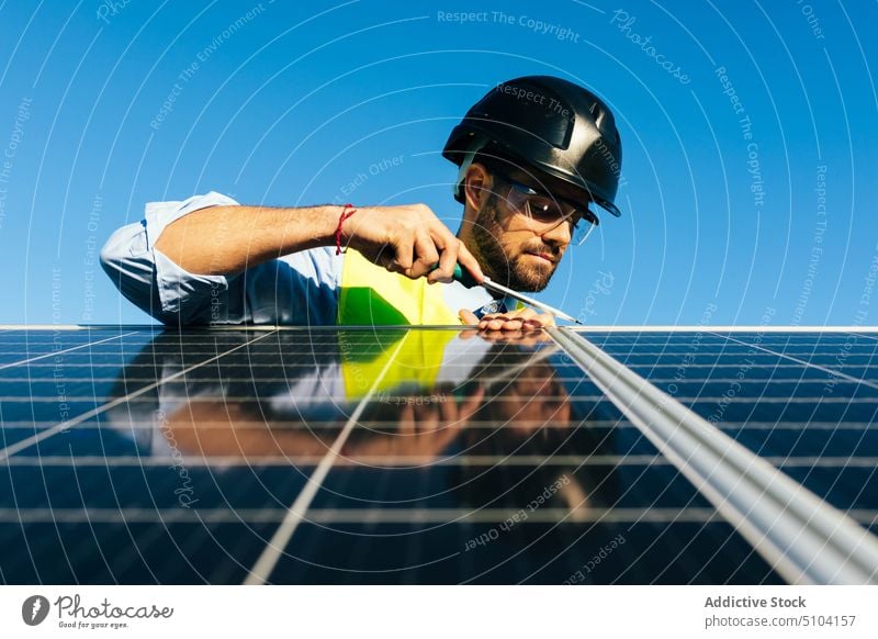 Solarmodul-Installateur bei der Arbeit Mann Techniker Photovoltaik Sonnenkollektor installieren Erneuerung Schraubendreher nachhaltig alternativ