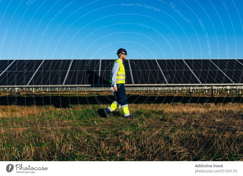 Techniker im Vorbeigehen an Photovoltaikzellen im Feld Mann Sonnenkollektor nachhaltig alternativ umweltfreundlich Energie Erneuerung männlich professionell Öko