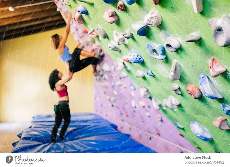 Sportlerin klettert mit Hilfe eines Trainers an der Wand Sportlerinnen Trainerin Aufsteiger Aufstieg abstützen Zusammensein Training Frau Hilfsbereitschaft