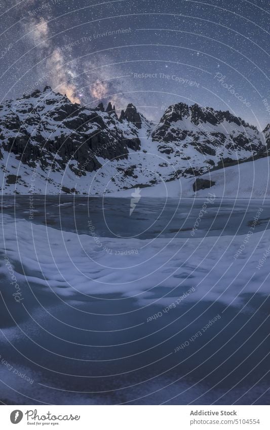 Verschneite Berge über einem See im Winter unter einem sternenklaren Milchstraßenhimmel Schnee Berge u. Gebirge trist Milchstrasse Seeufer gefroren kalt