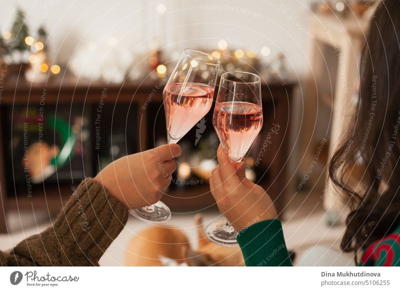 Zwei Gläser Rosensekt in der Hand, um auf Weihnachten oder Neujahr anzustoßen. Feiern auf einer Party. Alles Gute zum Geburtstag oder Jahrestag. Festliche Getränke Hintergrund. Feste und Feiern. Jubel mit Gläsern. Horizontal New Year Party Hintergrund.