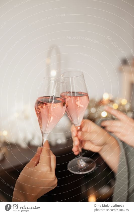 Zwei Gläser Rosensekt in der Hand, um auf Weihnachten oder Neujahr anzustoßen. Feiern auf einer Party. Alles Gute zum Geburtstag oder Jahrestag. Festliche Getränke Hintergrund