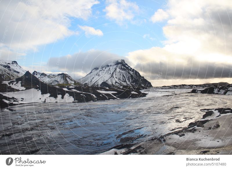 Ein Hauch von blauem Himmel gespiegelt im Schmelzwasser des Mýrdalsjökull Gletschers in Island mit schneebedeckten Bergen. Berge u. Gebirge