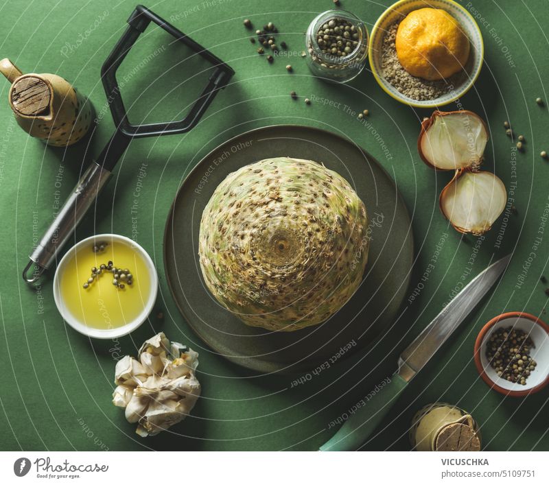 Raw celery roots vegetables on plate at green kitchen table background with ingredients and utensils, top view food vegetarian food healthy eating