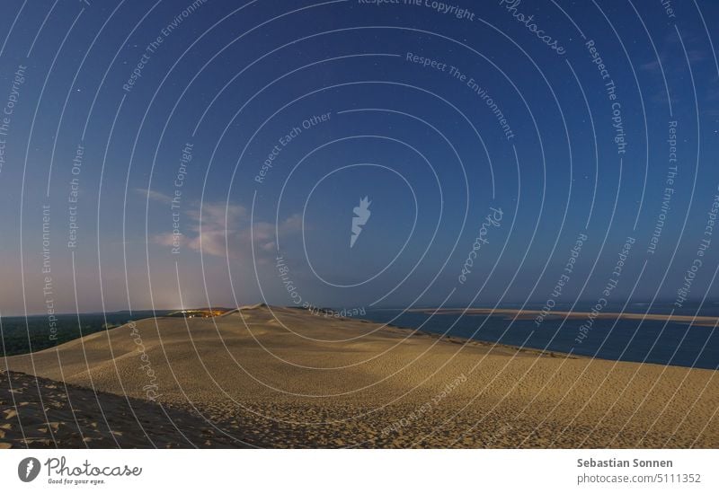 Nacht mit Sternen am Himmel auf einer riesigen natürlichen Sandformation Dune du Pilat, beleuchtet vom Mondlicht, Arcachon, Nouvelle-Aquitaine, Frankreich