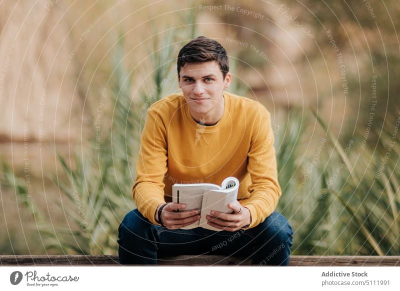 Mann liest Buch im Park Konzentration lesen Natur Hobby Bank Literatur männlich malerisch interessant lässig Roman Baum Fokus Freizeit Gras Buchse Typ