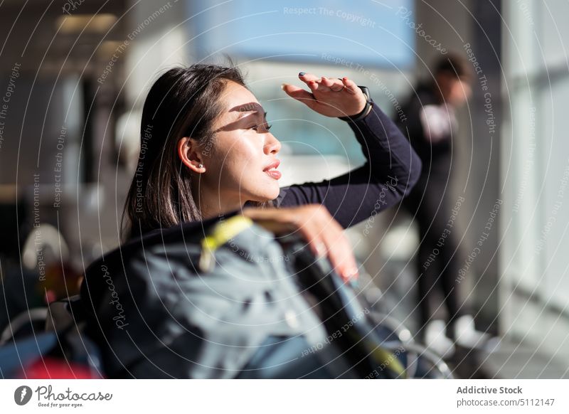 Asiatische Frau schaut im Flughafen weg Tourist Sonnenlicht Terminal Ausflug Lächeln warten behüten Wochenende jung asiatisch ethnisch Reisender Tourismus