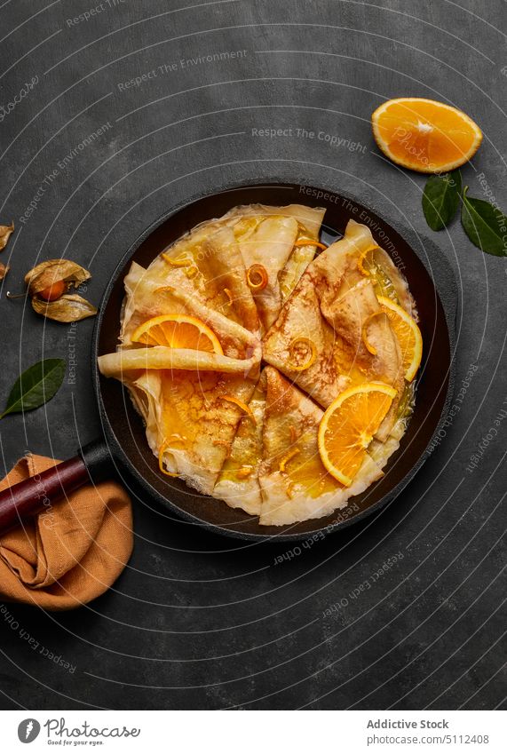 Hausgemachte Crêpes Suzette mit Orangenlikör und Orangenscheibe Pfanne serviert Beton Cointreau Gabel und Messer Europäer Zucker Textfreiraum Pfannkuchen heiß