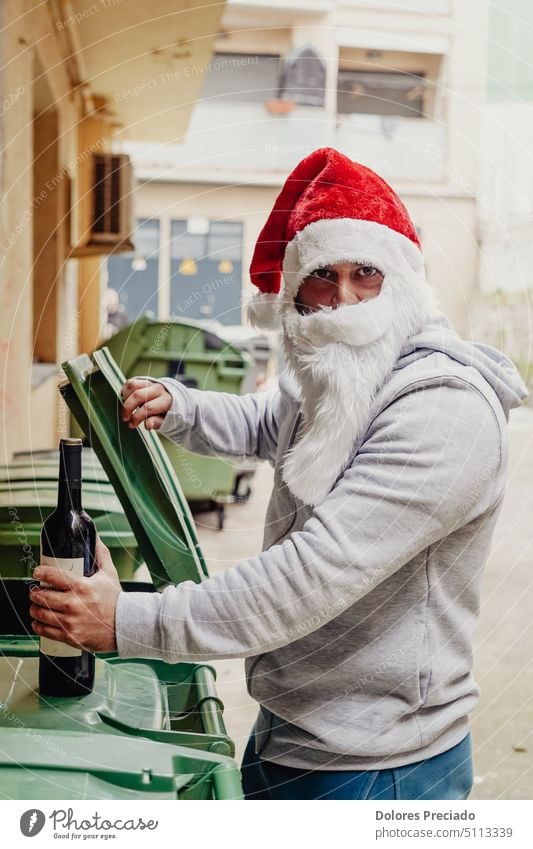 Obdachloser Weihnachtsmann trinkt Wein und durchwühlt Mülltonnen Alkohol alkoholisch böser Weihnachtsmann Vollbart Betteln Flasche brutal Kaukasier Feier