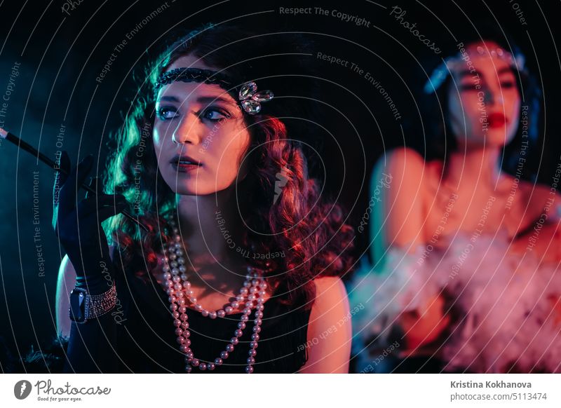 Porträt der jungen Flapper-Frauen im Stil des Großen Gatsby gekleidet posiert auf dunklen Velours Hintergrund. Roaring Twenties, Retro, Party, Modekonzept 1920s