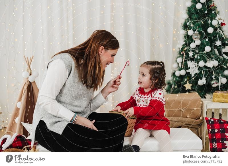 fröhliche mutter und tochter zu hause genießen die weihnachtszeit zu hause. sie geben dem kind süßigkeiten Weihnachten Familie heimwärts Mutter Tochter