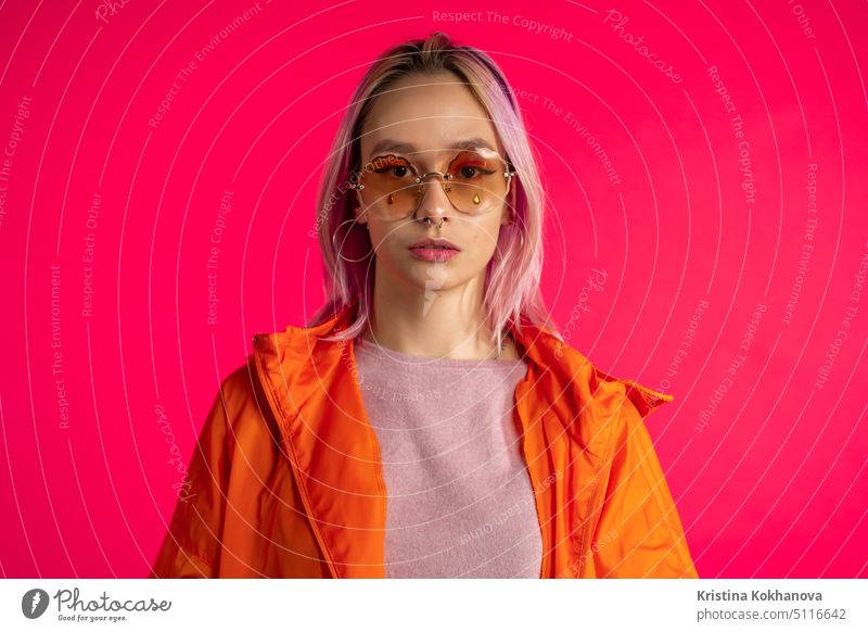 Porträt der hübschen ungewöhnliche Frau mit gefärbten Haaren auf viva magenta Studio Hintergrund. Trendy Neon bunte Frau mit Piercing, Brillen. Lebendige Aufnahme.