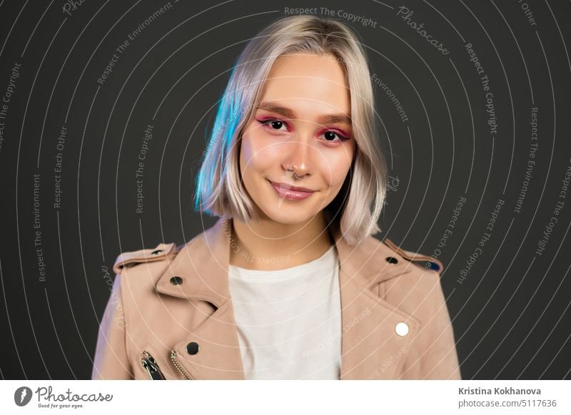 Schöne trendige Frau mit blondem Haar auf grauem Studiohintergrund. Hipster Mädchen Porträt. Mode, Stil, Freiheit, Jugend Konzept. Person Krapfen süß Dessert