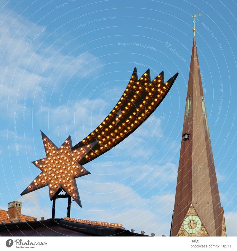 beleuchteter Schweifstern vor blauem Himmel mit Wolken, im Hintergrund ein Kirchturm Stern Komet Beleuchtung Weihnachtsbeleuchtung Weihnachtsdekoration