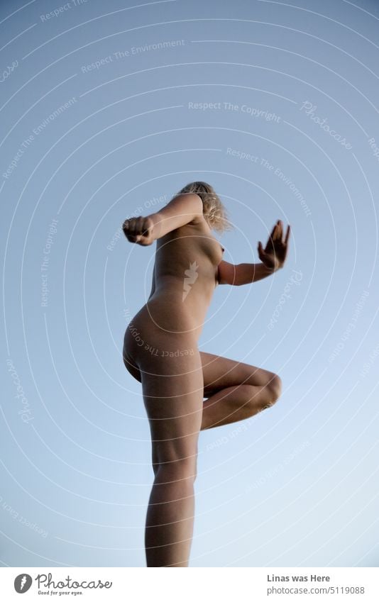 Wilde und sexy Bewegungen einer wunderschönen nackten Frau im Freien. Blauer Himmel als Hintergrund. Sexy Kurven als Motivation. So funktioniert dieses Bild.