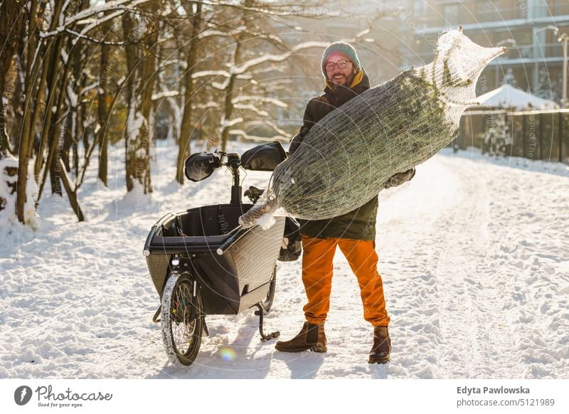 Mann transportiert Weihnachtsbaum auf Lastenfahrrad nachhaltiger Transport transportierend ökologisch Ökologie Kohlenstoff-Fußabdruck umweltfreundlich Lastenrad