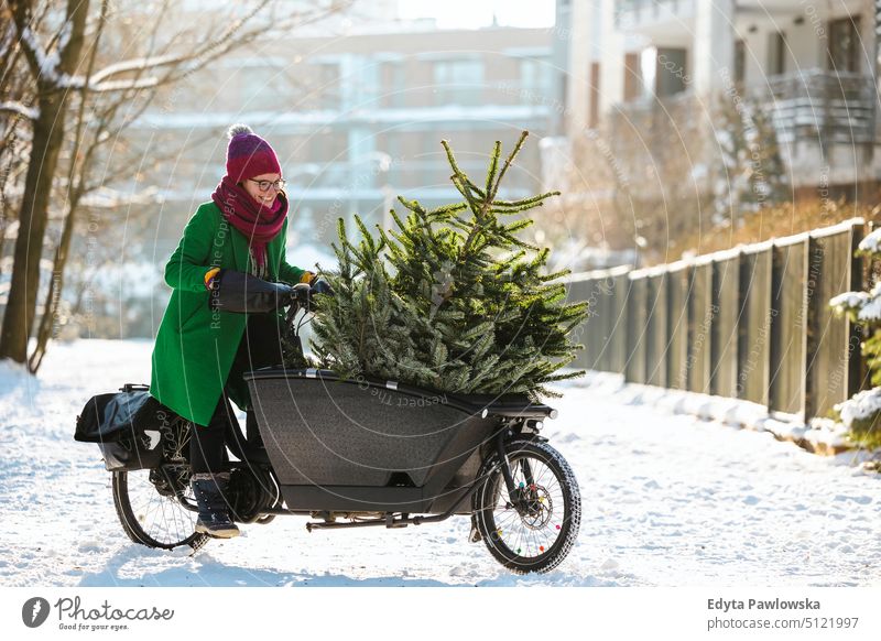 Frau transportiert Weihnachtsbaum auf Lastenfahrrad nachhaltiger Transport transportierend ökologisch Ökologie Kohlenstoff-Fußabdruck umweltfreundlich Lastenrad