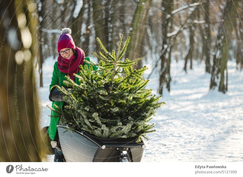 Frau transportiert Weihnachtsbaum auf Lastenfahrrad nachhaltiger Transport transportierend ökologisch Ökologie Kohlenstoff-Fußabdruck umweltfreundlich Lastenrad