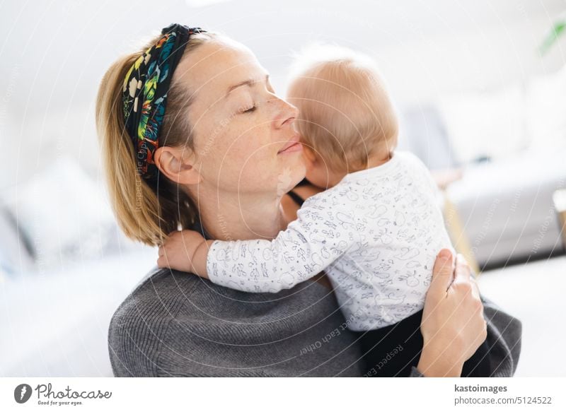 Baby ruht in den Armen der Mutter. Neue Mutter hält und umarmt kleines Kind mit Zärtlichkeit, Liebe, Pflege. Mutterschaft Konzept. Familie Junge Auge Mama jung