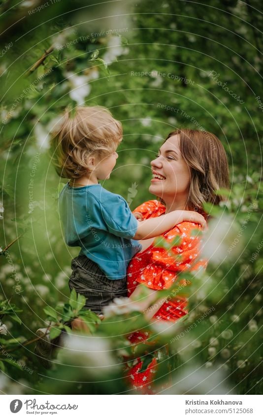 Porträt der glücklichen Mutter und ihr kleiner Junge. Schöne berührende Szene von Mutter und Sohn bewundert einander und aufrichtig lächelt. Blühender Garten im Frühling. Familie, Kuss, Kindheit Konzept.