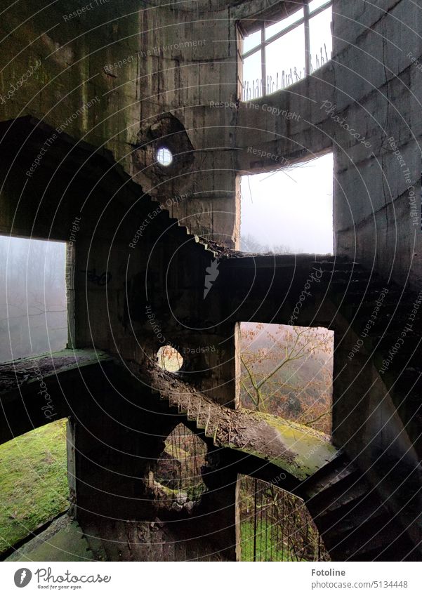 In dem alten Schornstein des Kraftwerks führen die Treppen weit nach oben. In dem alten Gemäuer sind große Löcher, durch die man die in Nebel gehüllte Landschaft draußen erkennen kann.