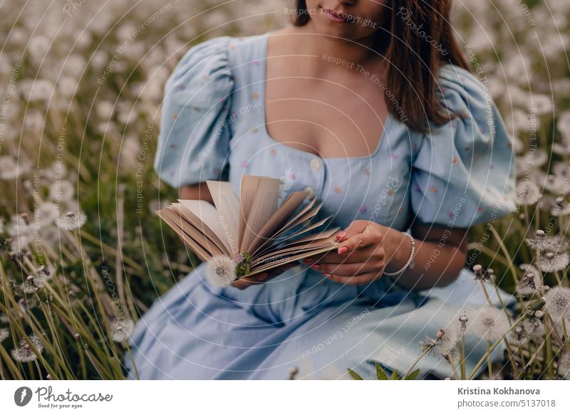 Frau blättert durch Seiten von Papier Buch. Dame im Retro- oder Vintage-Kleid liest interessanten Roman, während sie in der Natur sitzt. Atmosphärische Szene. Bildung, Hobby, Unterhaltung Konzept.