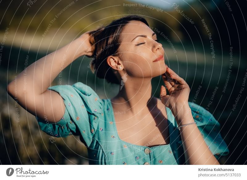 Porträt der jungen ländlichen elegante Frau posiert auf Natur Hintergrund. Sexy languid Dame berühren Haar, genießen Sommerzeit, Sonnenstrahlen. Vintage gestylten Kleid.