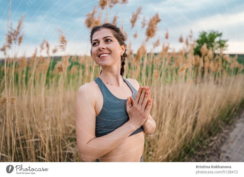 Junge Frau macht Namaste, Pranayama Yoga Atemübung auf Schilf natürlichen Hintergrund. Gesundes Mädchen Training im Sommer im Freien. Dankbarkeit, Einheit mit der Natur, Wellness-Konzept.