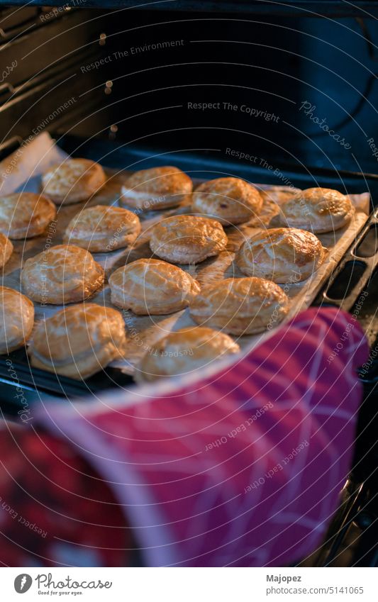 Menschliche Hand mit einem Ofenhandschuh, die ein Tablett mit Teigtaschen aus dem Ofen nimmt Mittagessen frisch Nahaufnahme Bäckerei Vorbereitung Koch