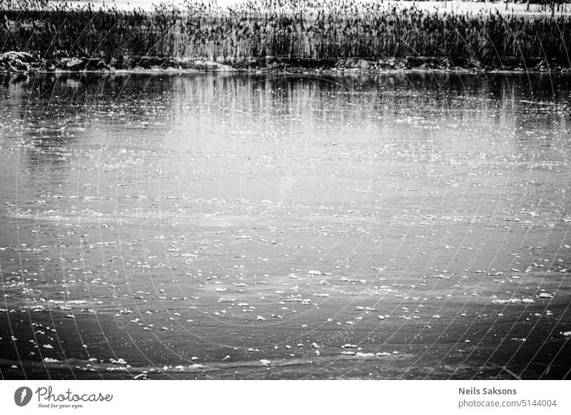 natürliche Schlittschuhbahn. Fluss Teich See mit Eis bedeckt dünnes Eis gefährlich Herausforderung Trotz Winter Frühwinter kein Schnee Monochrom