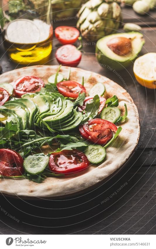 Gesunde Fladenbrot-Sandwich-Zubereitung mit frischer Tomate, Gurke und Avocado auf dunklem Hintergrund mit Zutaten, Nahaufnahme Gesundheit Belegtes Brot