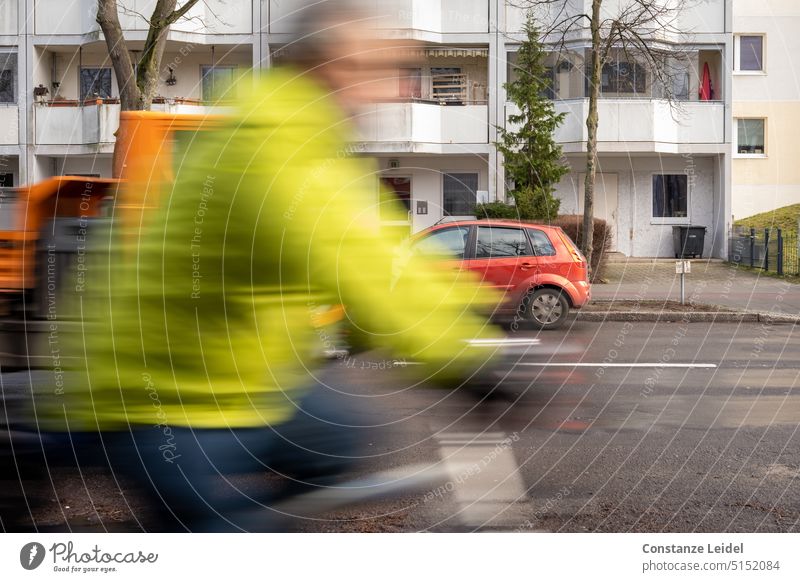 Radfahrer mit grüner Jacke in Bewegung. Radfahren Fahrrad Straßenverkehr Leuchtgrün Signalgrün Leuchtfarbe Leuchtfarben Autoverkehr Radverkehr Unschärfe