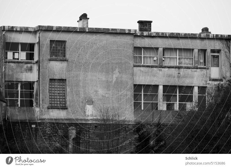 Triste Fassade mit Kindergarten trist Schwarzweißfoto marode Fenster Beton Schornsteine Tür Schule Grundschuhle Gebäude Wand Menschenleer Außenaufnahme Bauwerk