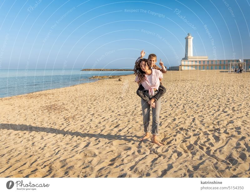 Glückliche Mutter und Sohn laufen am Strand barfuß in einem sonnigen Tag gegen den Leuchtturm Barfuß MEER Sonnenuntergang im Freien Kleinkind kleiner Junge Kind