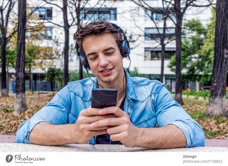 Mann hört Musik von einem Smartphone im Stadthintergrund Technik & Technologie Person Kopfhörer benutzend männlich Mobile Telefon Lifestyle Großstadt im Freien