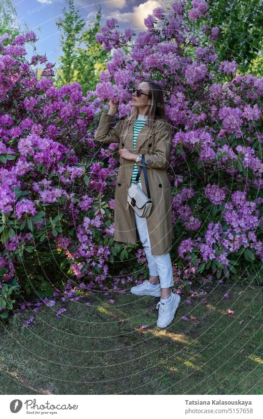 Eine Frau riecht an den violetten Blüten eines Rhododendronstrauchs Erwachsener lange Haare rhododendron Blumen Blütezeit Überstrahlung Buchse Strauch