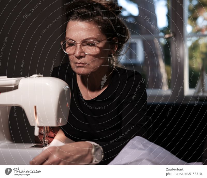 Die Näherin I - Frau sitzt mit konzentriertem Blick an der Nähmaschine nähen Hobby Hingabe Konzentration Handarbeit Nähen Handwerk Nadel Nähgarn Schneider Stoff