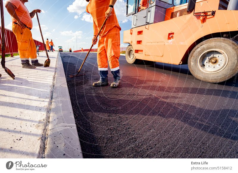 Arbeiter mit Harke richtet heißen Asphalt auf das richtige Maß aus ausrichten Ausrichten Ausrichtung Asphaltierung Bitumen Blacktop Brücke Baustelle Tiefbau