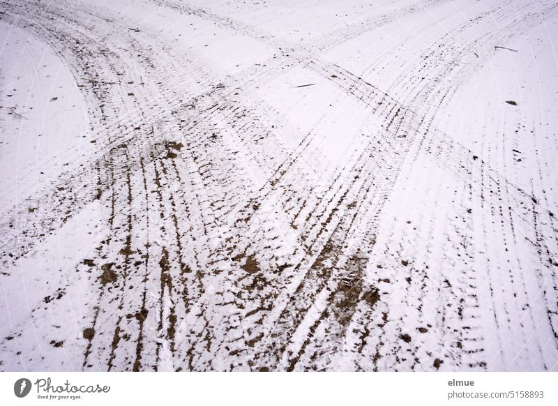 an einer Straßengabelung führen Reifenspuren im Schnee nach links und nach rechts / eine Entscheidung treffen Autospur Schneespur Abzweig Winter abbiegen Bogen