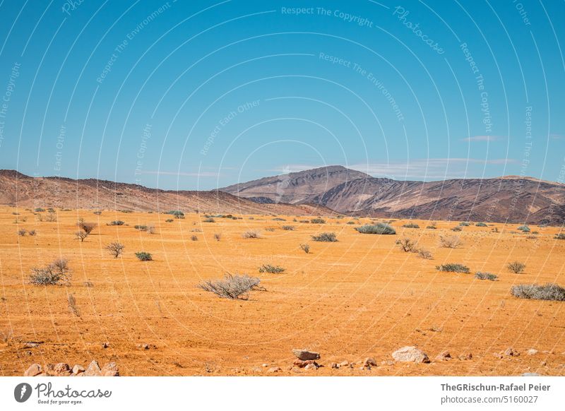 Wüste vor Berg Sand Berge u. Gebirge Himmel Busch Steine Wolken reisen Landschaft weite Ferien & Urlaub & Reisen Menschenleer Ferne Sommer Freiheit Namibia