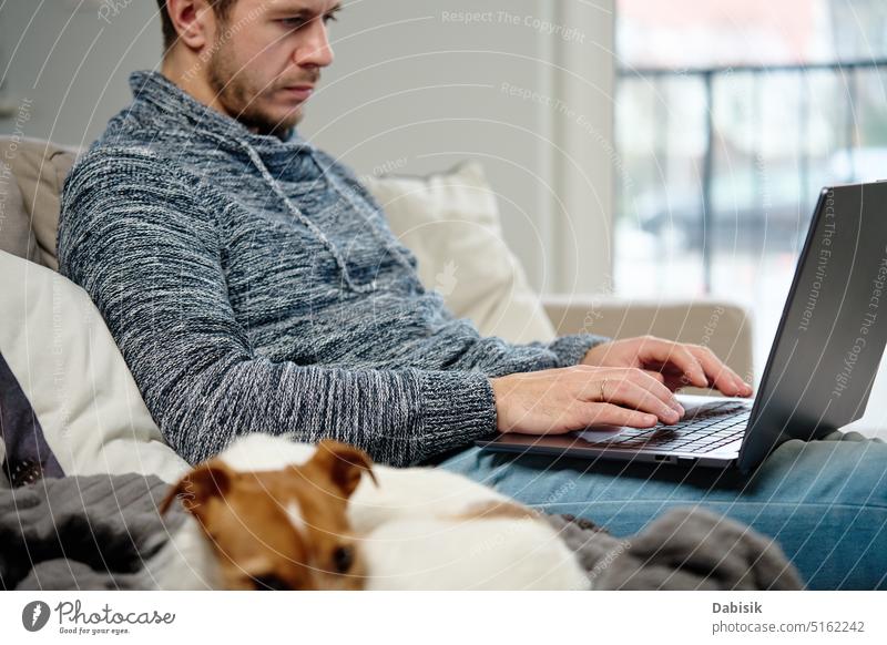 Mann benutzt Laptop im Wohnzimmer Arbeit heimwärts abgelegen Lifestyle online Freiberufler Arbeit von zu Hause aus Hund Haustier beschäftigt Business