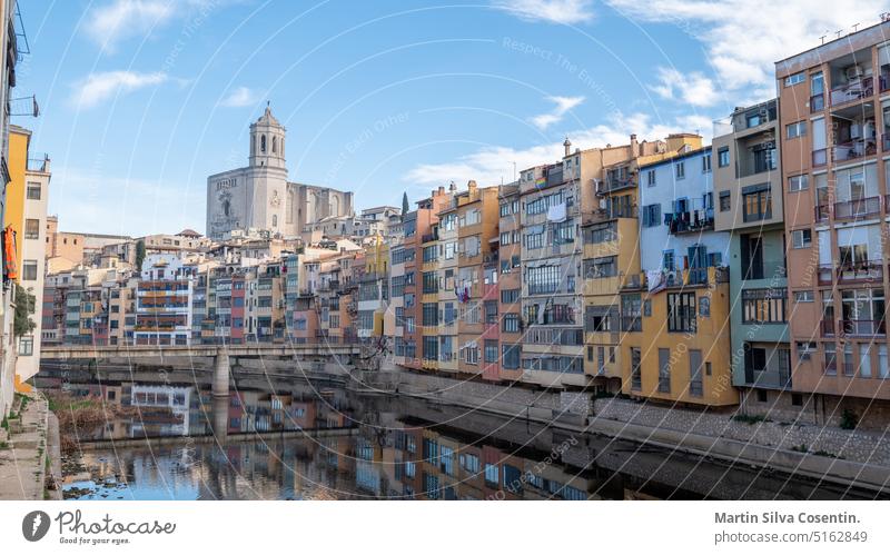 Bunte Häuser, die sich im Fluss Onyar spiegeln, in Girona, Katalonien, Spanien. Die Kirche Sant Feliu und die Kathedrale Santa María im Hintergrund antik