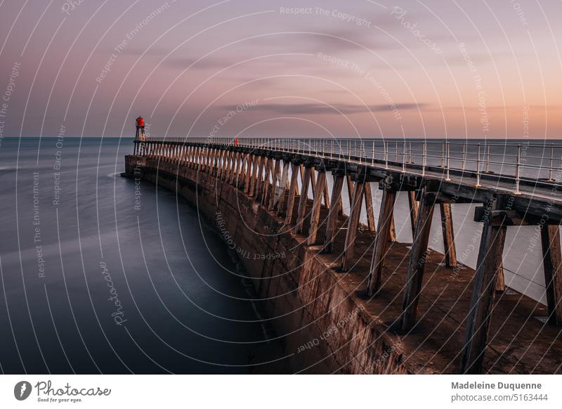 Der Leuchtturm bei der Hafeneinfahrt von Whitby (UK) bei Sonnenaufgang England United Kingdom Vereinigtes Königreich Pier Seefahrt Meer Wasser Geschichte