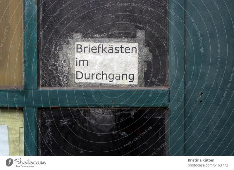 briefkästen im durchgang - infozettel klebt an der tür hinweis glastür hintertür fenster scheibe strukturglas geklebt zustellung post briefe zeitungen werbung